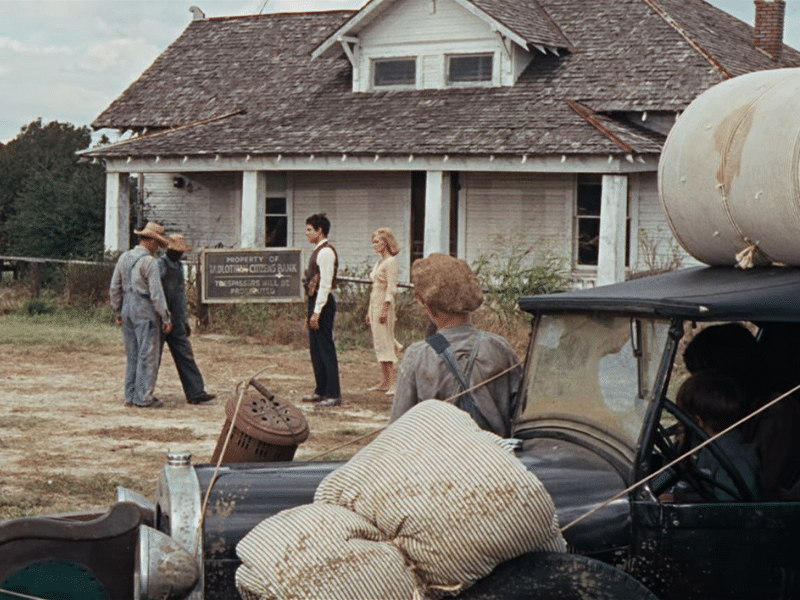 Scene from 'Bonnie and Clyde' depicting a tense standoff between characters in front of an old farmhouse.