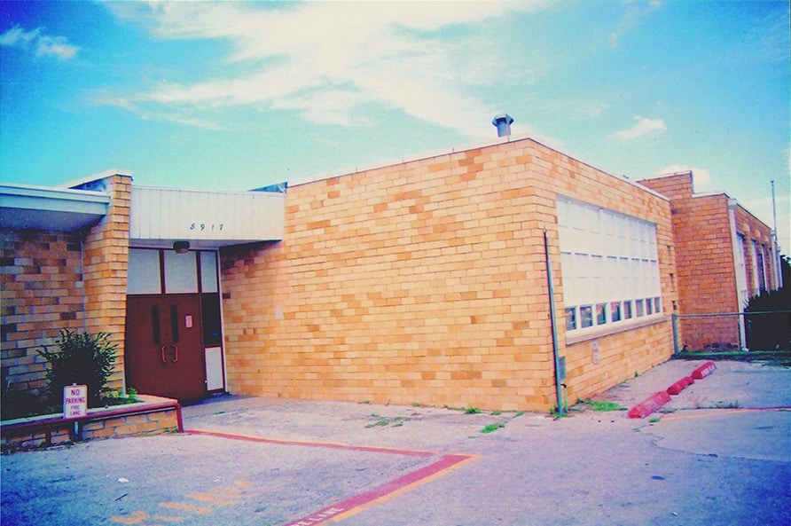 Exterior view of a brick school building with a clear sky, featuring a prominent entrance and windows.